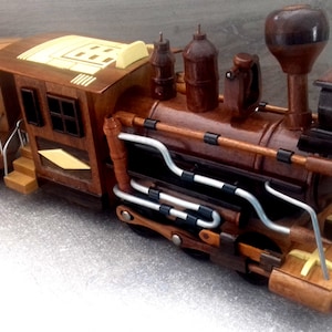 Op de afbeelding: Een houten speelgoedtrein met een bruine en gele passagierswagen. De trein is gemaakt van hout en heeft een gedetailleerd ontwerp. De trein staat op een grijs oppervlak.