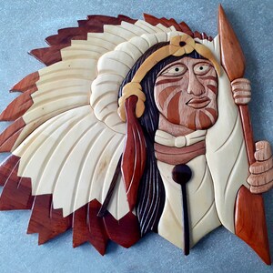 Peut inclure: Une sculpture en bois d'un chef amérindien portant une coiffe à plumes et tenant une lance. La sculpture est peinte dans des tons de brun, rouge et blanc.