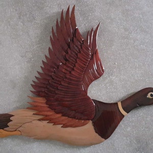 beautiful figurine of a duck in flight in different types of varnished wood