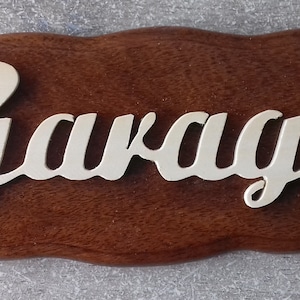 May include: A wooden sign with a wavy edge, painted brown. The word "Garage" is written in gold lettering.
