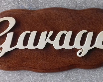 May include: A wooden sign with a wavy edge, painted brown. The word "Garage" is written in gold lettering.
