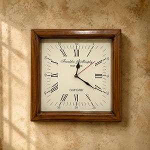 May include: A square wall clock with a dark brown wooden frame and an off-white face. The clock features black Roman numerals, minute markers, and the text Franklin & Murphy EST 1868 OXFORD. It has black hour and minute hands and a thin red second hand.