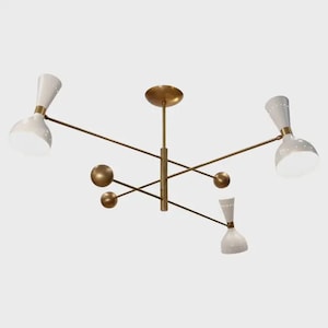 May include: A mid-century modern ceiling light fixture. It features four white, cone-shaped shades with brass accents and a brass central structure. The fixture has a minimalist design with a focus on geometric shapes and clean lines.