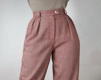 May include: High-waisted trousers in a muted dusty rose color with a subtle herringbone texture. These pants feature a structured waistband with a single centered button closure, belt loops, and two vertical pleats on the front of each leg.