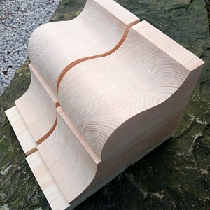 Puede incluir: Dos piezas de madera sin terminar con un diseño curvo. Las piezas están apiladas una encima de la otra y tienen una veta de madera natural.