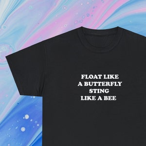 May include: Black t-shirt with the text "FLOAT LIKE A BUTTERFLY STING LIKE A BEE" in white, centered on the chest. The shirt is a classic crew neck style, suitable for casual wear.