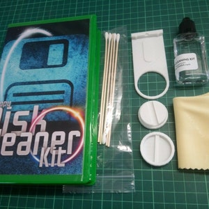 May include: A green and blue floppy disk cleaner kit with a floppy disk icon on the front. The kit includes a cleaning solution, two cleaning pads, a cleaning brush, and a microfiber cloth.