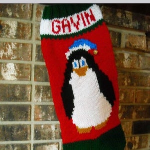 May include: A red, green, and white knitted Christmas stocking with a penguin design. The stocking has the name "Gavin" embroidered on the top.