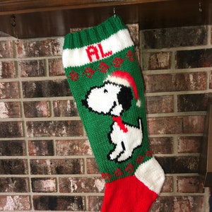 May include: Green and red knitted Christmas stocking with a white Snoopy design and the name "AL" on the cuff.
