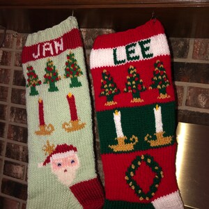 May include: Two knitted Christmas stockings with the names "Jan" and "Lee" on them. The stockings are decorated with green and red stripes, Christmas trees, candles, and a Santa Claus face.
