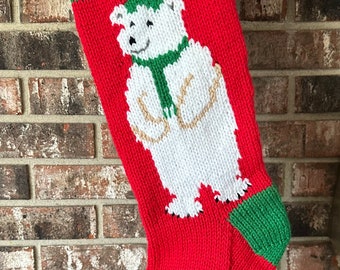 May include: Red and green knitted Christmas stocking with a white polar bear design and the name "JON" embroidered on the stocking.