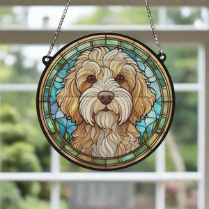 Può includere: Una finestra in vetro colorato appesa con un motivo floreale colorato e un ritratto di un cane color crema con occhi marroni.