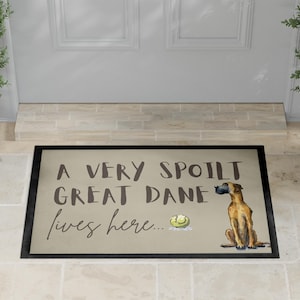 May include: Doormat with a black border, featuring the text "A VERY SPOILT GREAT DANE lives here...". The mat displays a watercolour illustration of a Great Dane dog and a tennis ball.