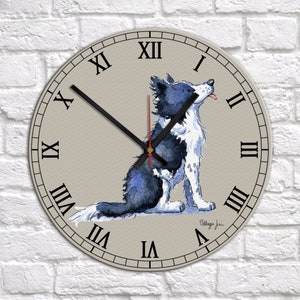 May include: A round wall clock with Roman numeral markings and a watercolor illustration of a blue and white border collie dog. The clock face is beige with a black and red clock hand.
