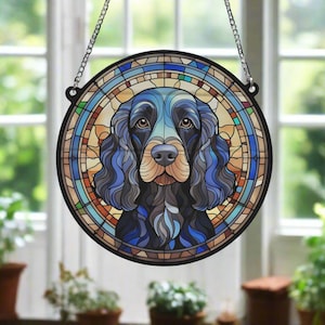 Peut inclure: Une fenêtre en verre coloré suspendue avec un chien cocker spaniel bleu et noir sur un fond de vitrail coloré.