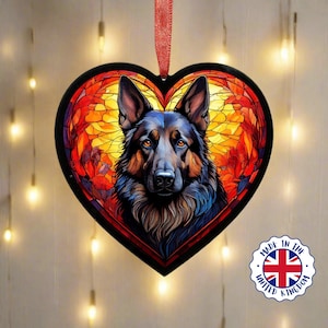 Può includere: Un ornamento di vetro a forma di cuore con un design a vetri colorati che presenta un pastore tedesco. Il cane è nero e marrone con un petto bianco e uno sfondo rosso, arancione e giallo.