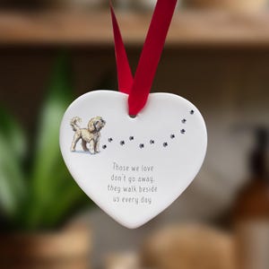 Könnte beinhalten: Weißer Keramik-Herzen-Anhänger mit einer kleinen Illustration eines Hundes und dem Text "Those we love don't go away, they walk beside us every day".