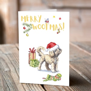 Könnte beinhalten: Eine Weihnachtskarte mit einem Hund, der einen Weihnachtsmann-Hut trägt und ein Geschenk hält. Die Karte sagt "Frohe Woofmas!" in goldenen Buchstaben.