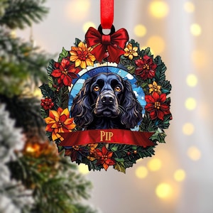 Könnte beinhalten: Runder Weihnachtsschmuck mit einem schwarzen Hund in der Mitte, umgeben von einem Kranz aus roten und gelben Blumen. Der Name des Hundes, "PIP", steht auf einem roten Banner. Oben befinden sich ein rotes Band und eine Schleife.