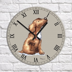 May include: A round wall clock with Roman numeral markings and a brown and white dog illustration. The clock face is beige with a light brown border. The text "Village Jun" is printed in the lower right corner.
