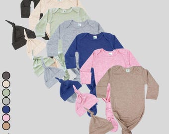 May include: Set of seven baby knotted gowns in various colors, including gray, green, blue, pink, and brown. Each gown is made of a soft, stretchy fabric and features a matching knotted hat. The gowns are perfect for newborns and infants.