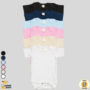 May include: A stack of six short-sleeved baby onesies in different colors: black, navy blue, light blue, pink, beige, and white. The onesies are made of 100% cotton and feature a round neckline and snap closures. The onesies are arranged in a vertical stack, with the black onesie at the top and the white onesie at the bottom.