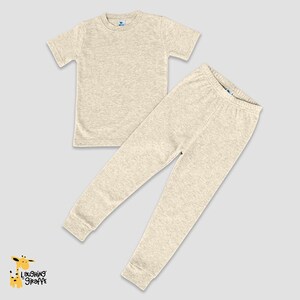 May include: A two-piece pajama set in a light beige color. The set includes a short-sleeved t-shirt and long pants.