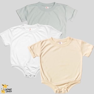 May include: Three blank baby onesies in different colors: light blue, white, and beige. The onesies have short sleeves and snap closures.