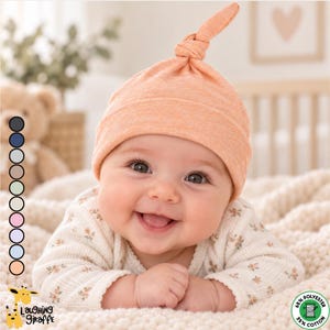 May include: A peach-colored baby hat with a top knot, paired with a long-sleeved white shirt featuring a small floral pattern. The hat is made of a blend of 65% polyester and 35% cotton. A vertical column of ten circular color swatches is visible.