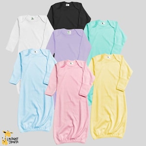 May include: A collection of baby gowns in various pastel colors, including white, black, light blue, lavender, mint green, pink, and yellow. Each gown has long sleeves and a rounded neckline. The gowns are made of soft fabric.