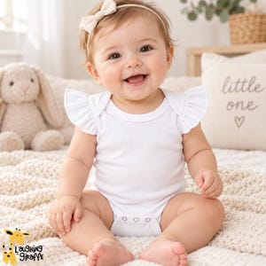 May include: A white baby bodysuit featuring short flutter sleeves and a round neckline. The garment has a snap-button closure at the bottom. The fabric is plain and solid white, designed with a simple cut for ease of movement and comfort.