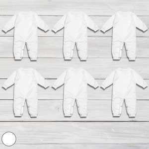 May include: Six white long-sleeved baby onesies laid out on a white wood background.