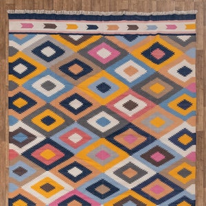 May include: A colorful geometric patterned rug with a navy blue, yellow, pink, white, and gray color scheme. The rug has a fringe border and measures 8x10 feet or 250x300 centimeters.