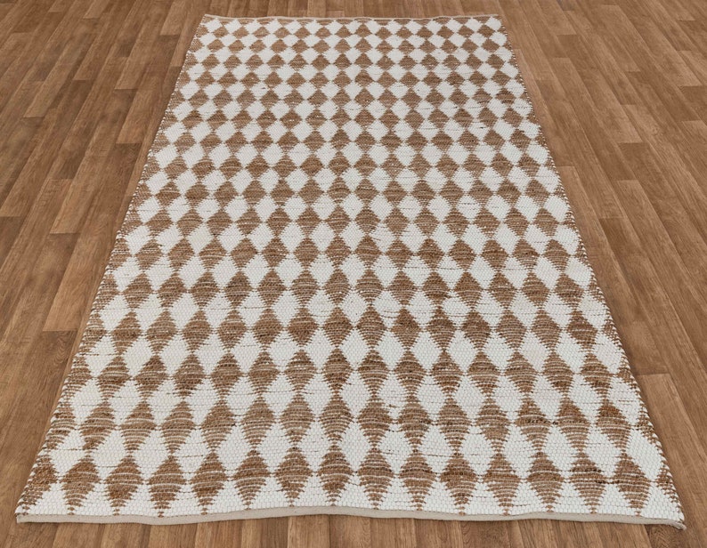 May include: A brown and white diamond patterned jute rug. The rug has a woven texture and is made of natural fibers.