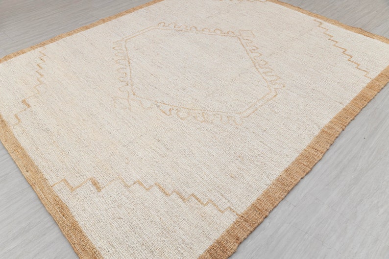 May include: A white rug with a beige border and a geometric design in the center.