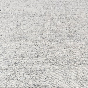 May include: A white and gray textured rug with a subtle pattern. The rug is made of a soft, woven material.