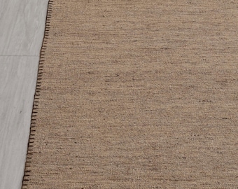 May include: A brown woven rug with a dark brown stitched border.