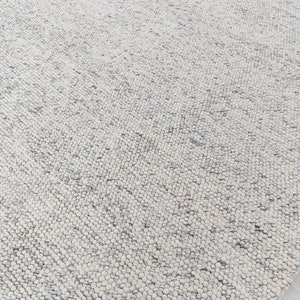 May include: A white and gray textured rug with a subtle pattern. The rug is made of a soft, fluffy material.