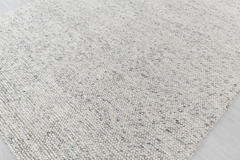 May include: A white and gray textured rug with a subtle pattern. The rug is made of a soft, fluffy material.