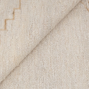 May include: A close-up of a white rug with a subtle geometric pattern in a light beige color. The rug is made of a soft, textured material.