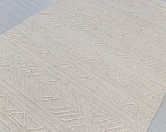 May include: A white woven rug with a geometric pattern. The rug has a subtle texture and a fringe border.
