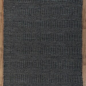Op de afbeelding: Een zwart-wit geometrisch patroon tapijt met een geweven textuur. Het tapijt heeft een subtiele glans en is gemaakt van natuurlijke vezels.