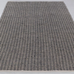 Puede incluir: Una alfombra rayada en blanco y negro hecha de fibras naturales. La alfombra tiene una textura tejida y un dise&ntilde;o simple.