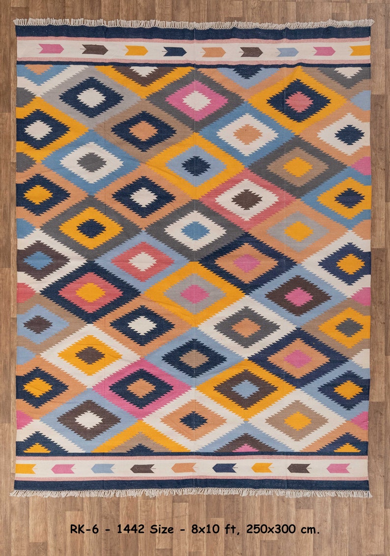 May include: A colorful geometric patterned rug with a navy blue, yellow, pink, white, and gray color scheme. The rug has a fringe border and measures 8x10 feet or 250x300 centimeters.