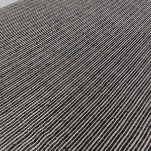 Puede incluir: Una alfombra de yute natural y negro con un patr&oacute;n de rayas. La alfombra est&aacute; hecha de fibras naturales y tiene una superficie texturizada.