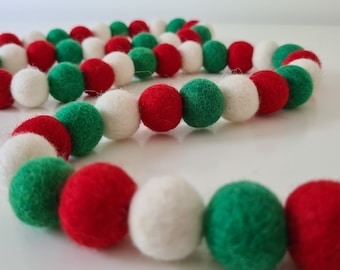 May include: A festive garland made of felt balls in red, white and green colours. The garland is perfect for decorating for the holidays.