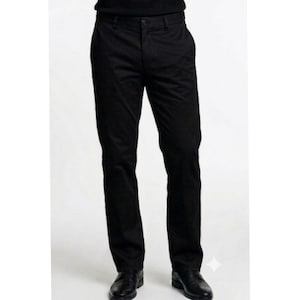 Può includere: Un paio di pantaloni neri a tinta unita con vita standard e passanti per cintura, chiusura frontale con bottone e cerniera e due tasche laterali. I pantaloni hanno un taglio a gamba dritta e sono abbinati a scarpe eleganti in pelle nera.