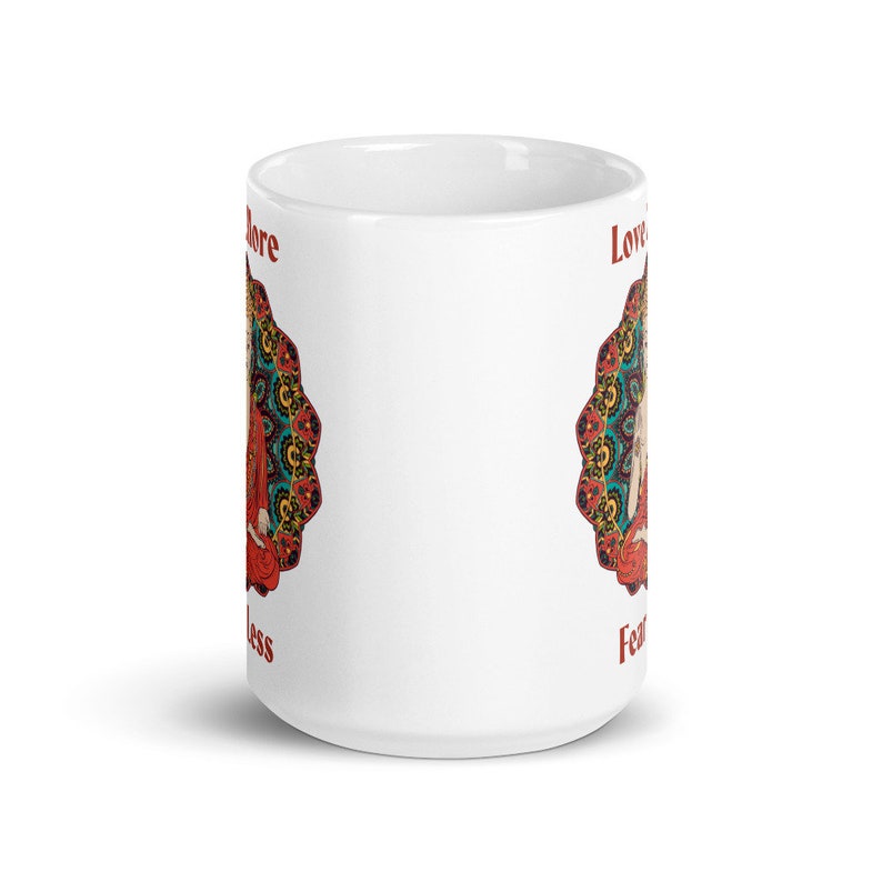 love more fear less coffee mug with handle by goddess swag. colorful buddha image with mandala behind it. Love More is written in a deep red above the buddha image and fear less is written in a deep red below the buddha image. Double sided.