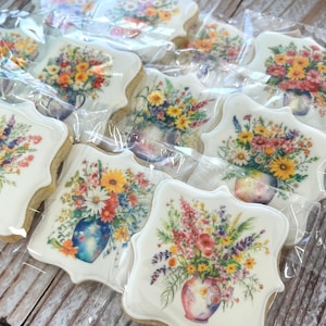May include: Assortment of decorated sugar cookies with floral designs. Each cookie features a different floral arrangement in a vase, with a white background and a scalloped edge.