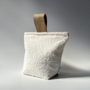 Ivory boucle fabric doorstop with jute handle.